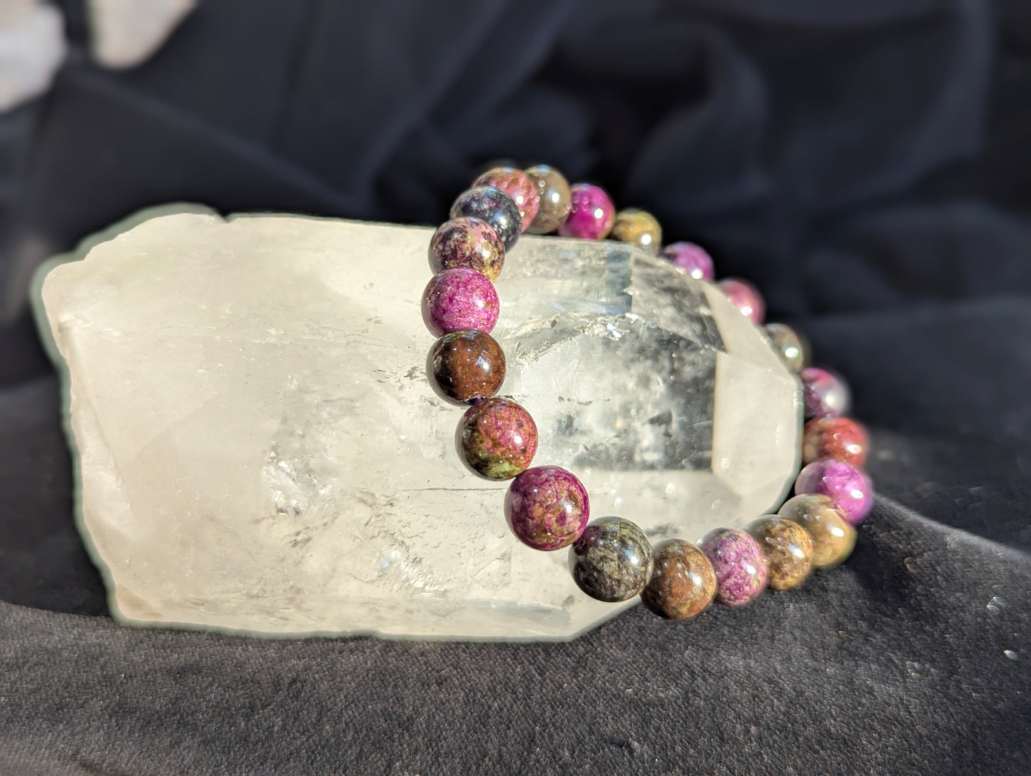 An alternate display angle of the premium 9.5mm Atlantisite beaded stretch bracelet resting on a presentation surface, emphasizing the continuous polish and natural matrix colours under balanced lighting.