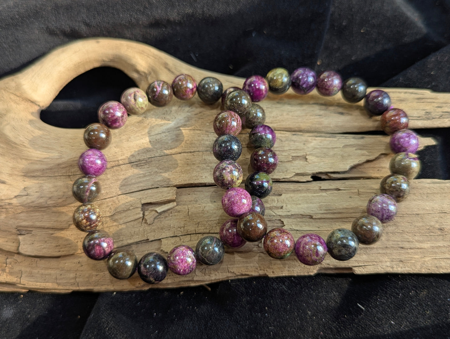 A 9.5mm Atlantisite round bead stretch bracelet positioned on a neutral presentation surface, demonstrating bead uniformity and the stark contrast between green serpentine and purple stichtite.
