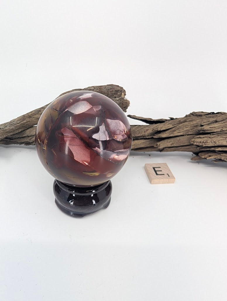 Intricate red and cream swirl patterns on a Mookaite sphere.