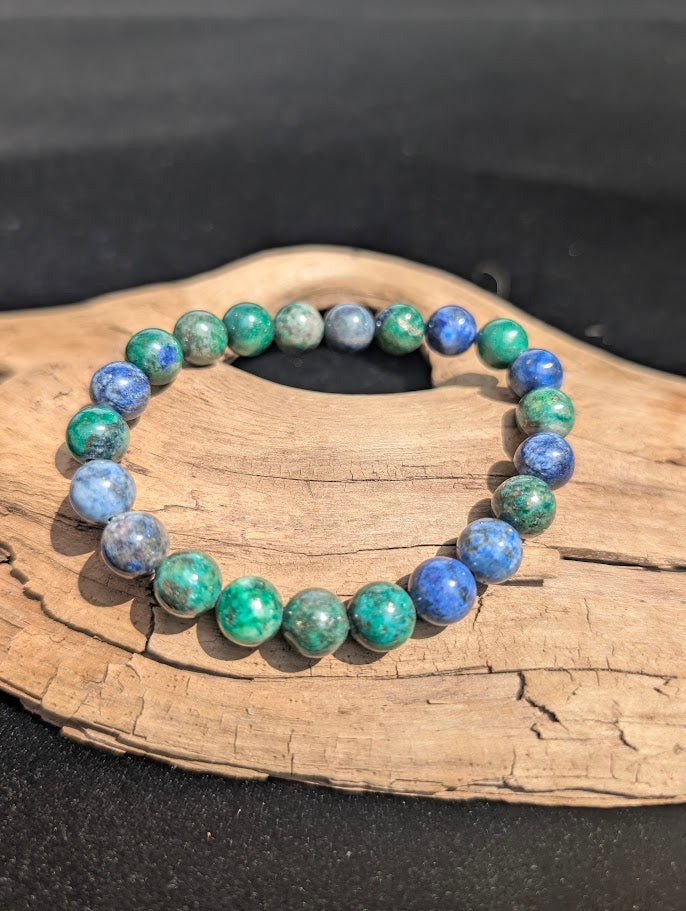 8mm Azurite-Malachite beaded bracelet resting on natural driftwood, showcasing a natural mix of deep blue and vibrant green colours.