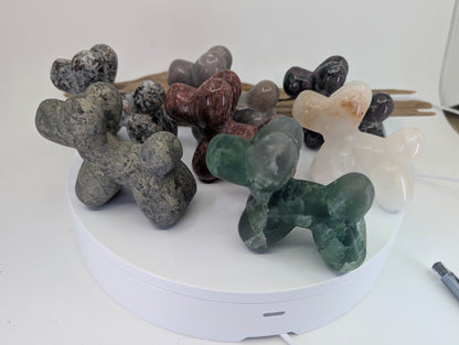 A diverse collection of hand-carved mineral balloon dogs in various stones for collector selection.