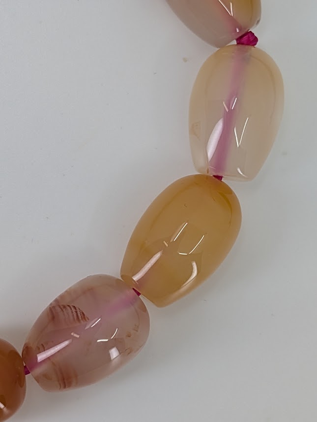 Detail view of agate bead translucence and soft peach-to-rose zoning
