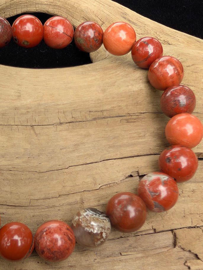 Macro close-up of 8mm polished Banded Red Jasper beads highlighting the high-gloss finish and natural hematite and quartz banding.
