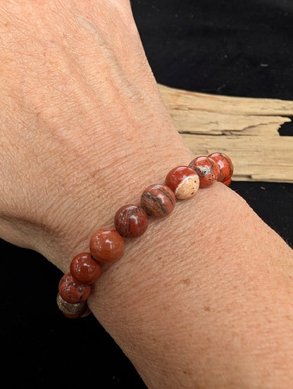 8mm polished Banded Red Jasper beaded stretch bracelet worn on a wrist for size scale.