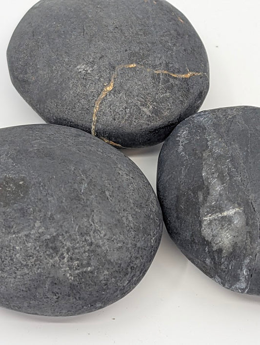 Bitumen palm stones with natural variation and slight golden fissure patterns
