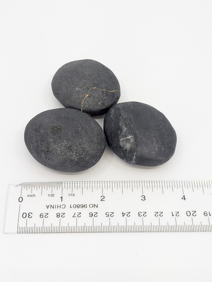 Three bitumen palm stones grouped together, highlighting surface texture and tone
