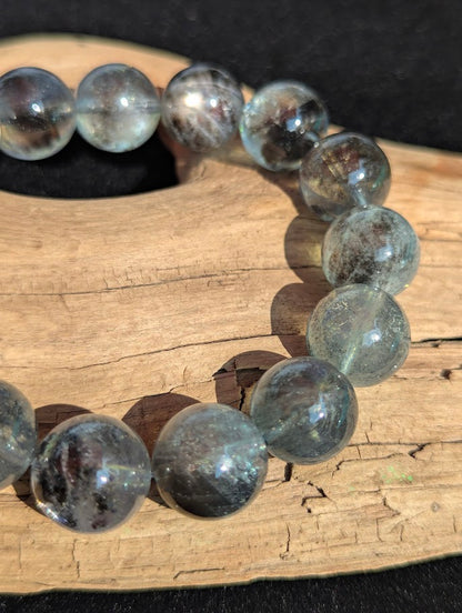Macro photograph of 12mm Black Devil Aquamarine beads highlighting rolling silver girasol chatoyancy and high surface polish.