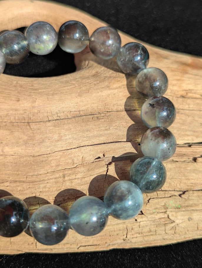 Macro detail of 13mm Brazilian Black Devil Aquamarine beads capturing the billowy silver internal sheen and dark mineral inclusions.