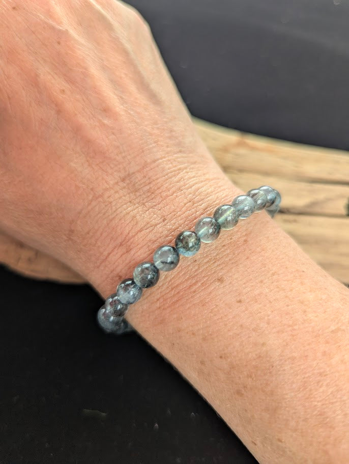 7mm AAA Grade Brazilian Girasol Black Devil Aquamarine beaded stretch bracelet worn on a wrist for scale demonstration.