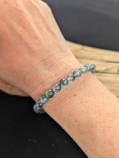 7mm AAA Grade Brazilian Girasol Black Devil Aquamarine beaded stretch bracelet worn on a wrist for scale demonstration.