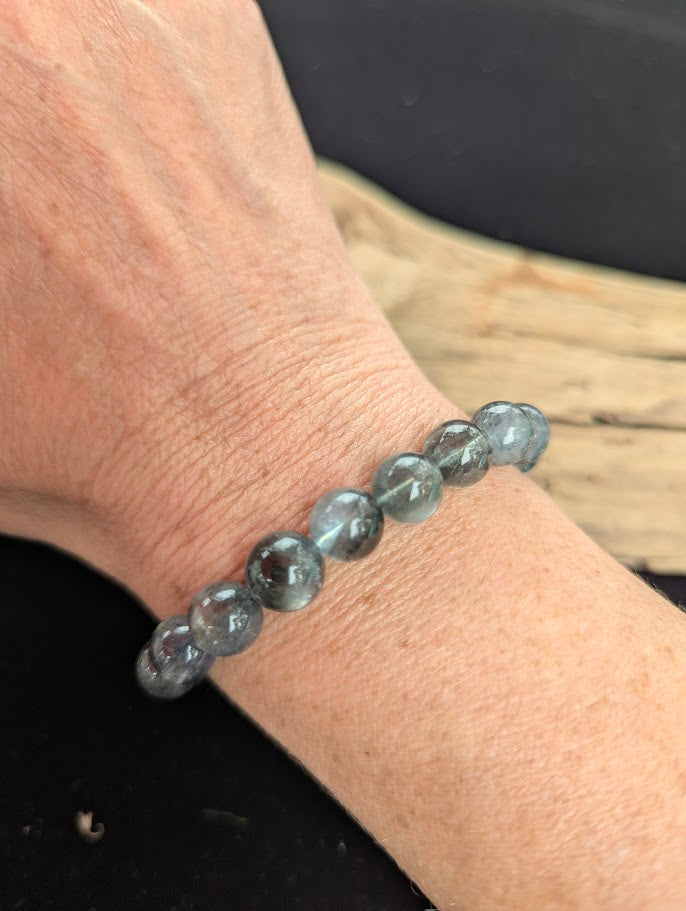 9mm AAA Grade Brazilian Girasol Black Devil Aquamarine beaded stretch bracelet worn on a wrist in natural lighting.