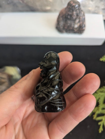 Side profile of a Black Obsidian Laughing Buddha figurine highlighting the detailed carving of the Hotei's robes and rounded form.