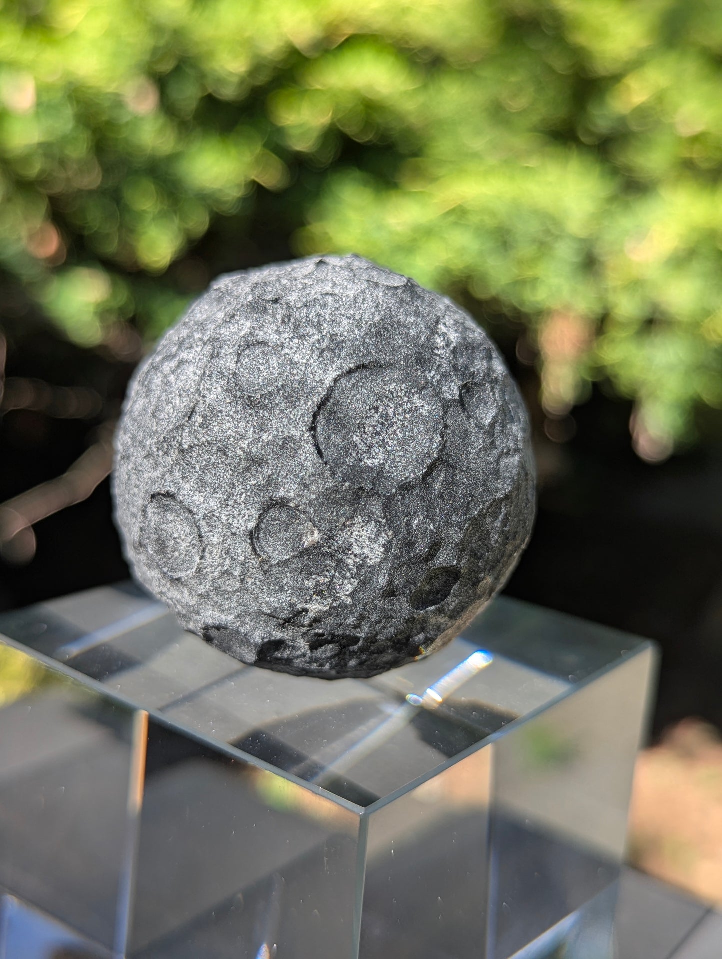 A 50 mm (1.97 in) opaque Black Obsidian carved moon sphere featuring an unpolished, textured crater design.
