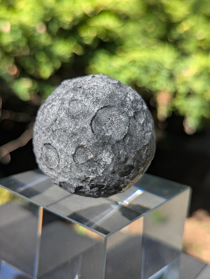 A 50 mm (1.97 in) opaque Black Obsidian carved moon sphere featuring an unpolished, textured crater design.