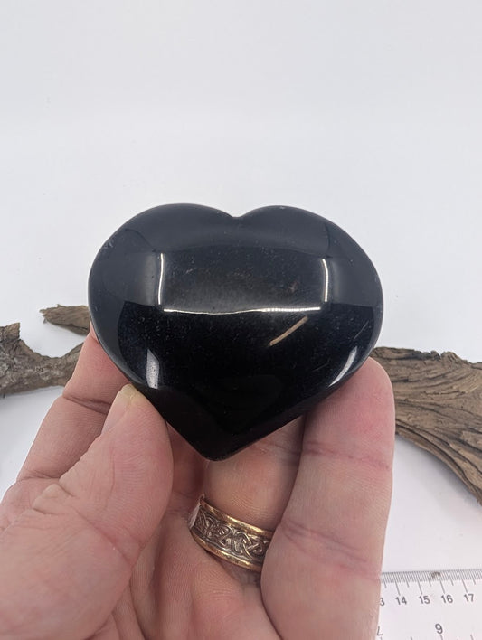 Hand holding a 120g Black Obsidian heart showing substantial size and reflection.