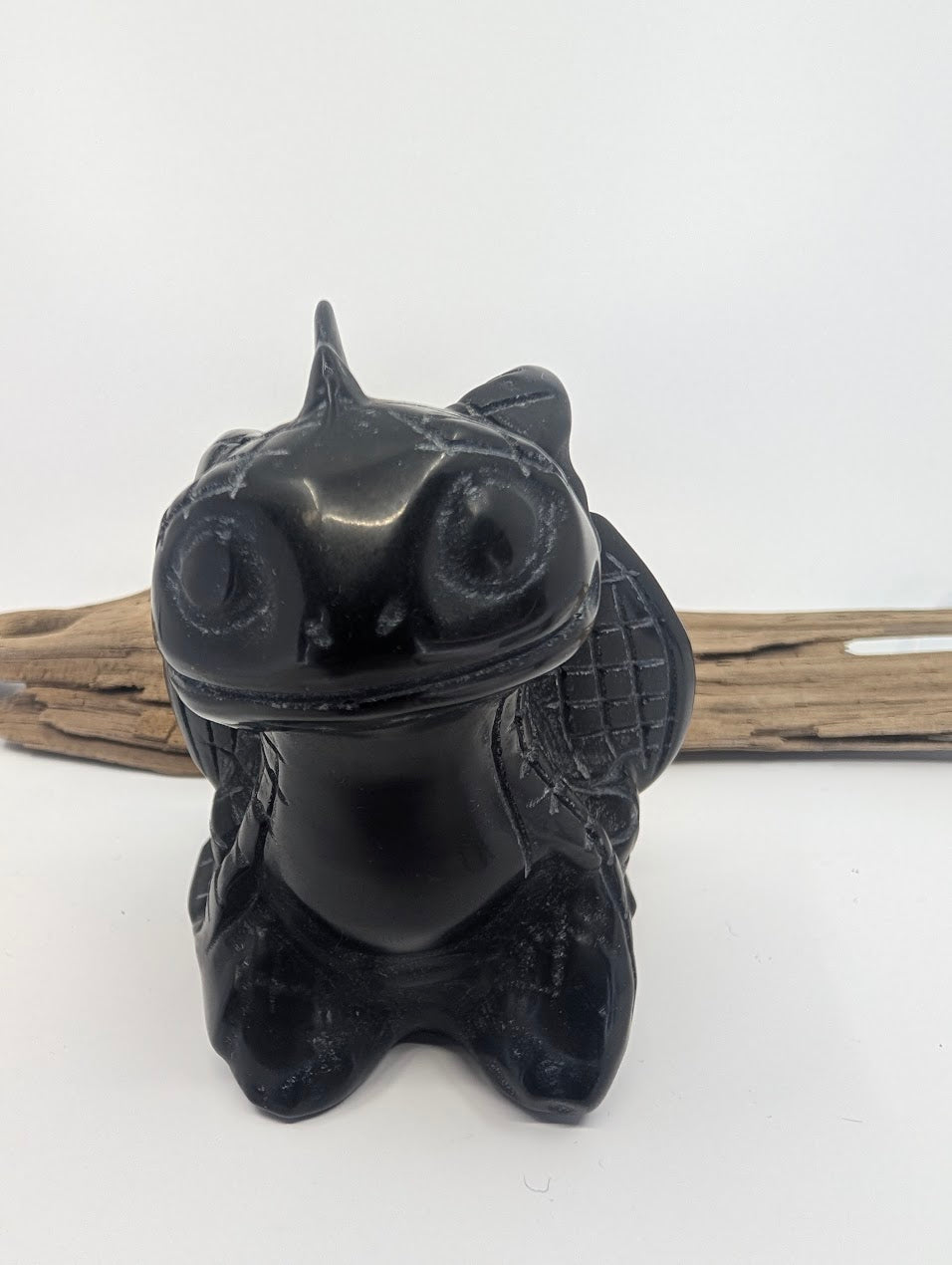 Close-up direct face view of the Toothless Obsidian carving featuring symmetrical hand-carved details.