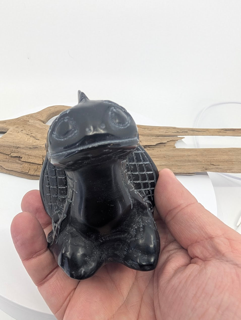 Hand-held view of the Black Obsidian Toothless carving providing a clear scale reference for the 9cm specimen.