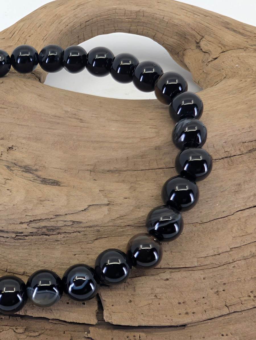Close-up of 6mm Black Onyx beads highlighting natural grey banding and authentic agate inclusions.