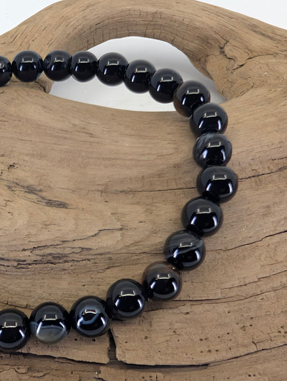 Close-up of 6mm Black Onyx beads highlighting natural grey banding and authentic agate inclusions.