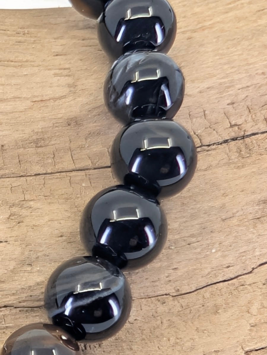 Macro view of 6mm Black Onyx beads showing professional mirror finish and "eye" inclusions typical of natural agate.