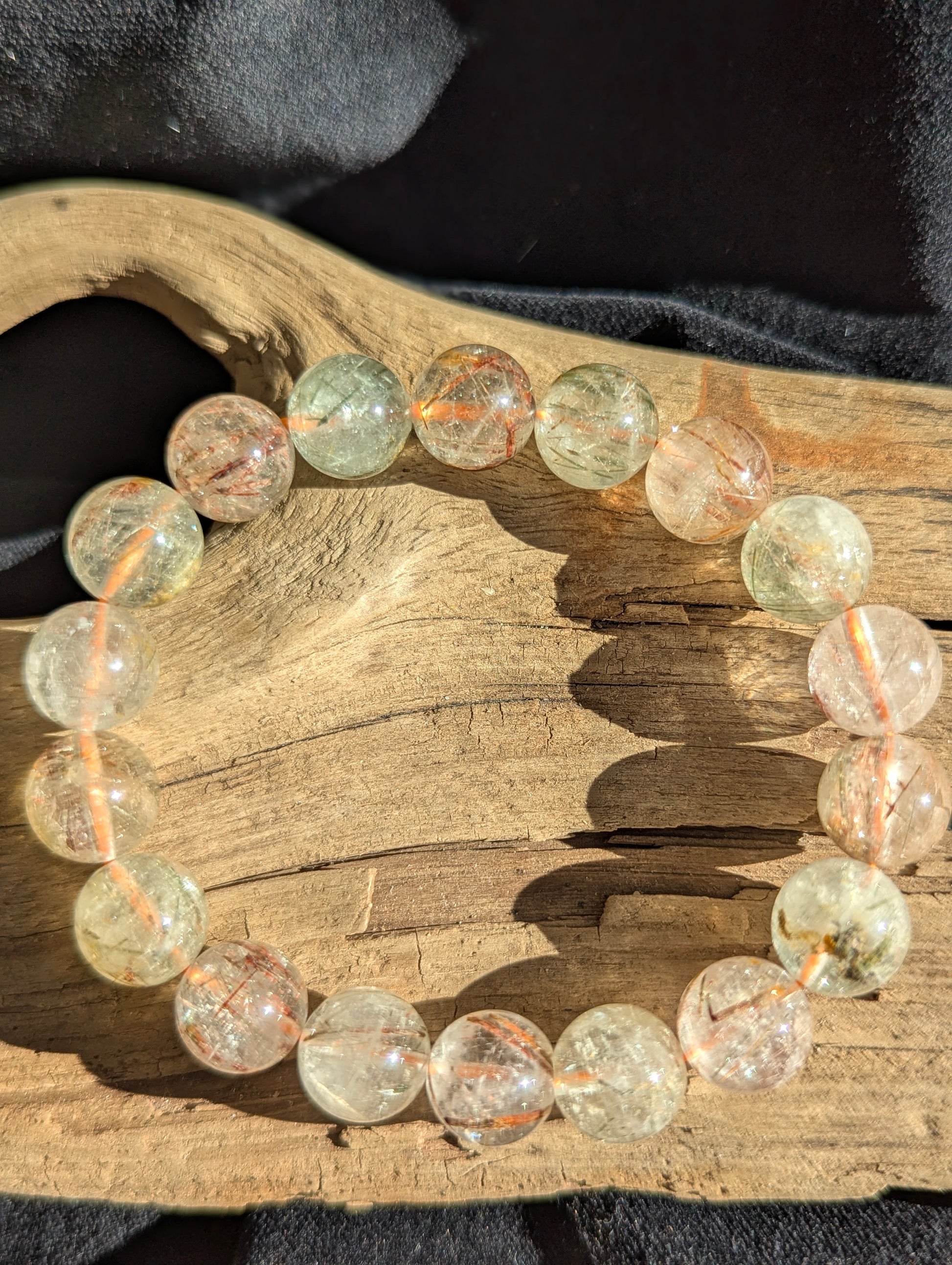 A 12mm bead stretch bracelet featuring vivid copper and black rutile needle inclusions suspended within a flawless transparent quartz matrix from Brazil