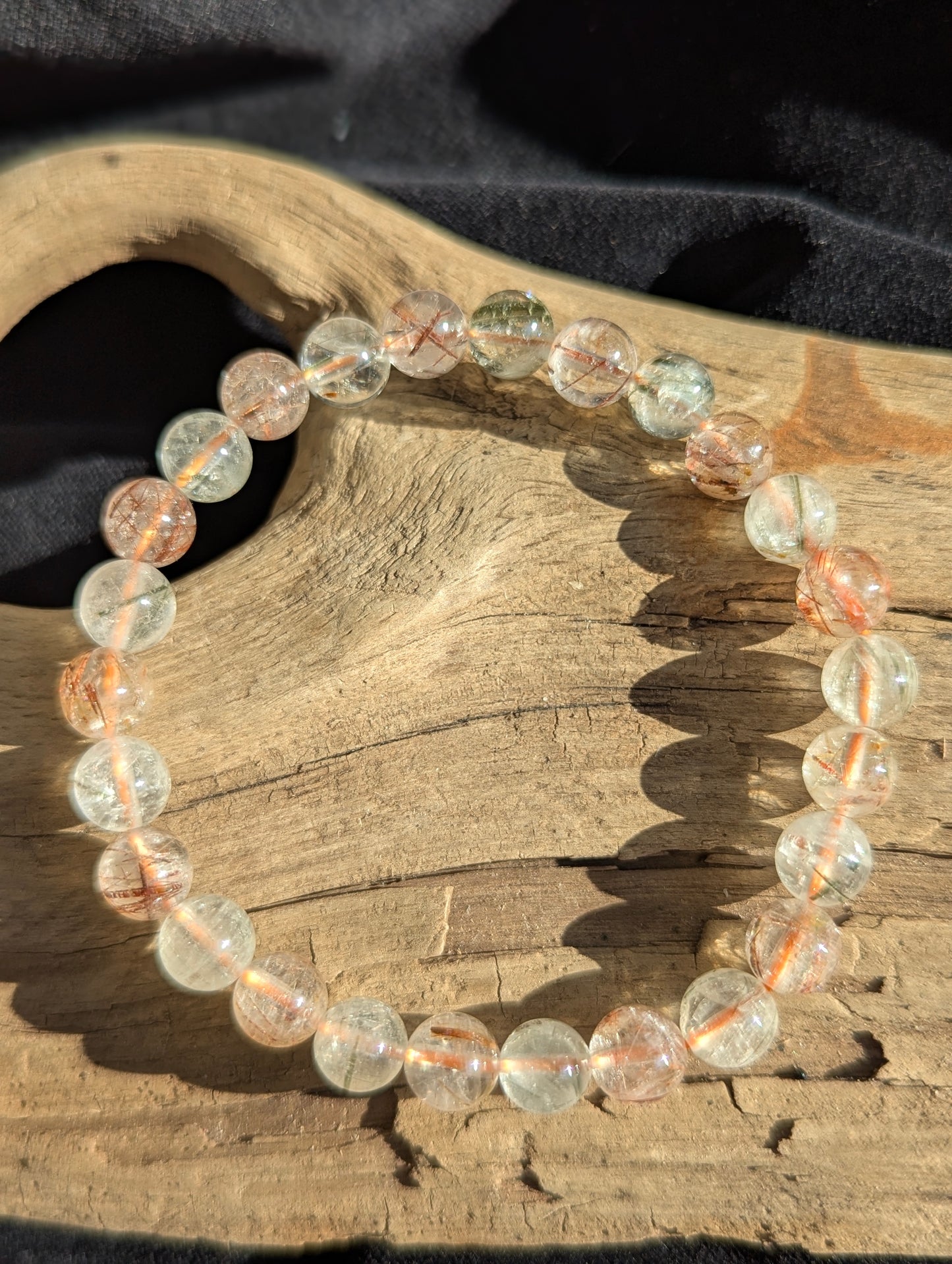An 8mm bead stretch bracelet made of clear macrocrystalline quartz from Brazil, heavily included with natural black and red rutile crystals.