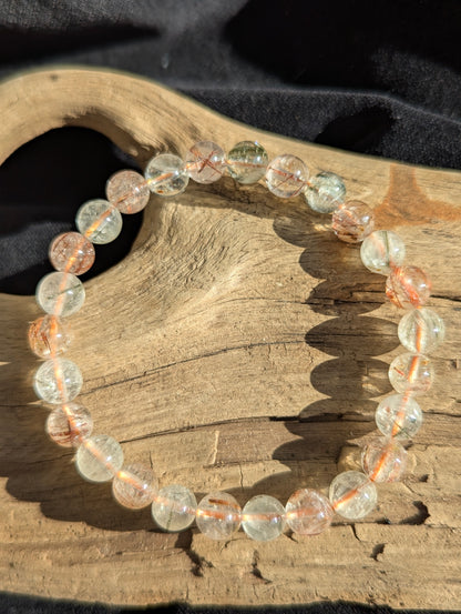 An 8mm bead stretch bracelet made of clear macrocrystalline quartz from Brazil, heavily included with natural black and red rutile crystals.