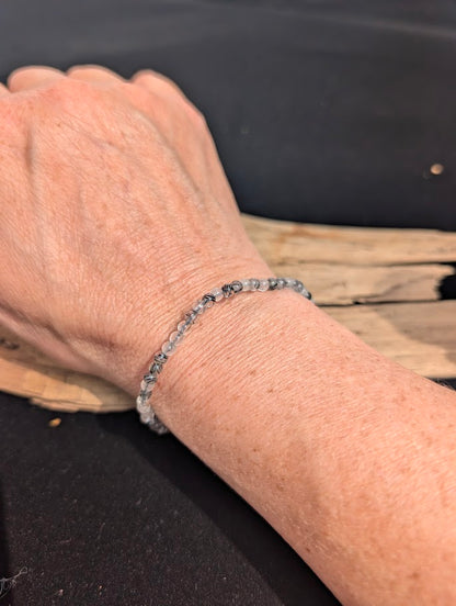 Natural sunlight on a 4mm translucent and black Tourmalinated Quartz stretch bracelet worn on a wrist.