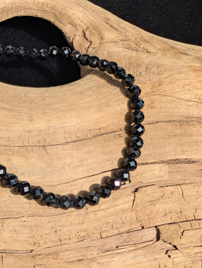 Macro close-up of 3mm faceted Black Tourmaline beads catching the light.