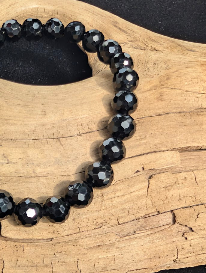 Macro close-up of 8mm faceted Black Tourmaline beads highlighting the geometric surface cuts.
