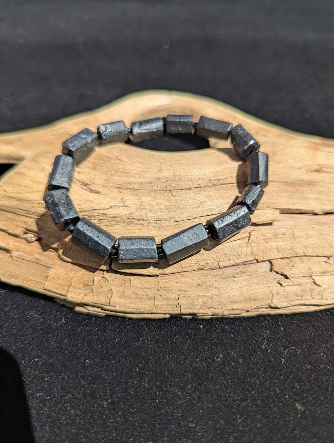 Polished Black Tourmaline geometric prism stretch bracelet resting on a driftwood display, showing a deep black, metallic luster.
