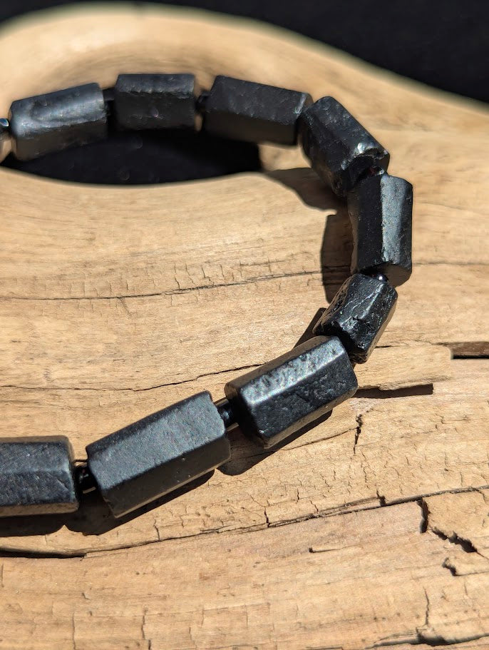 Macro close-up of Black Tourmaline prism beads highlighting the geometric, flat-faceted cut and the high-gloss surface polish.