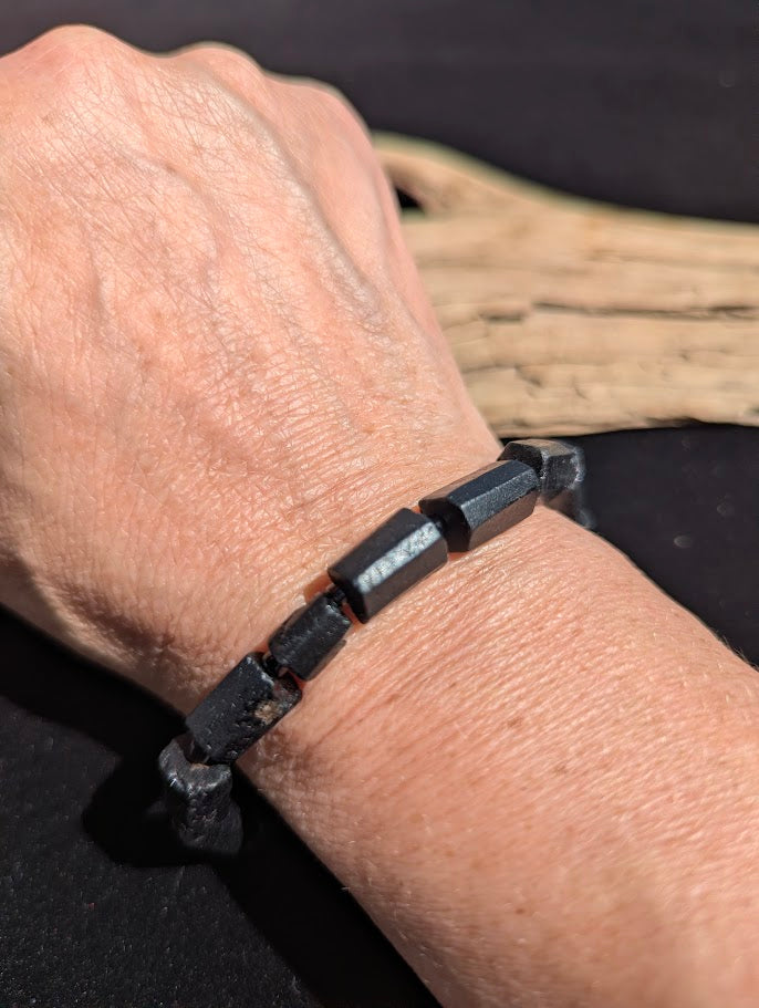 Polished Black Tourmaline geometric prism stretch bracelet worn on a wrist for size scale.