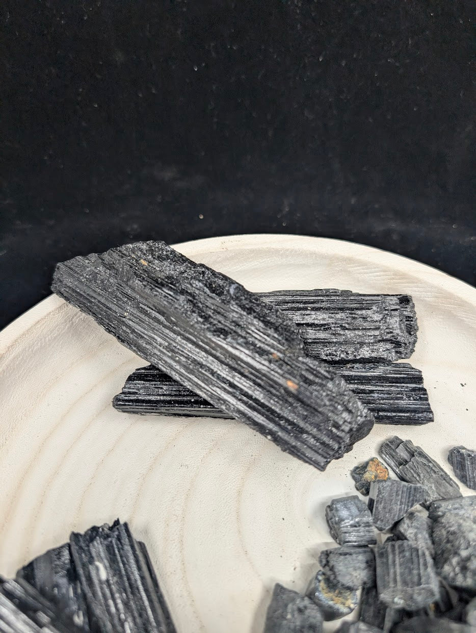 Top-down view of elongated Black Tourmaline rods highlighting the prismatic crystal habit and naturally fractured ends.