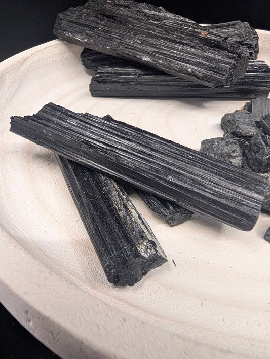 Close-up of small raw Black Tourmaline rods showing high-luster surfaces and distinct vertical c-axis striations.