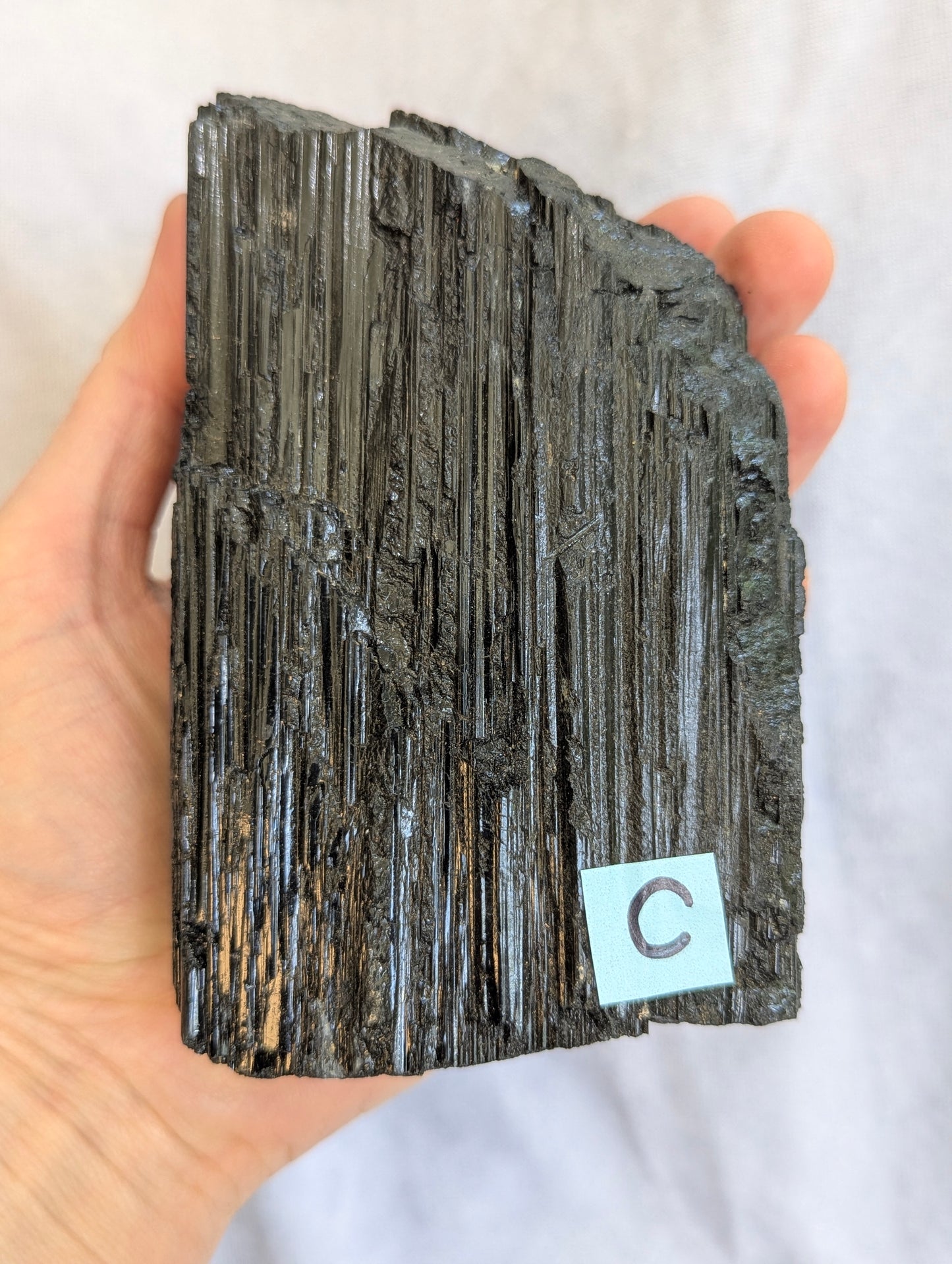 Hand Held Scale reference view of 1.11kg raw Black Tourmaline tower on display.