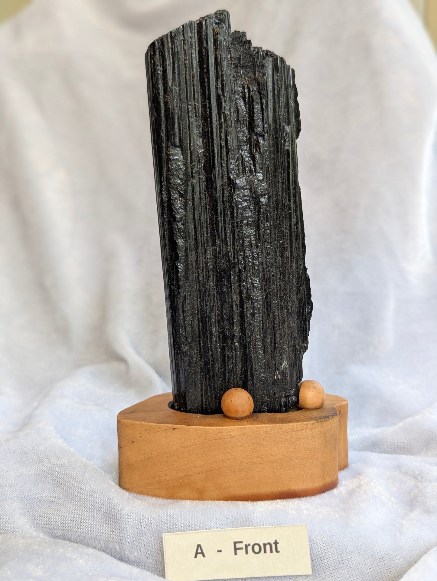 390g raw Black Tourmaline tower with deep longitudinal striations on custom wooden stand.