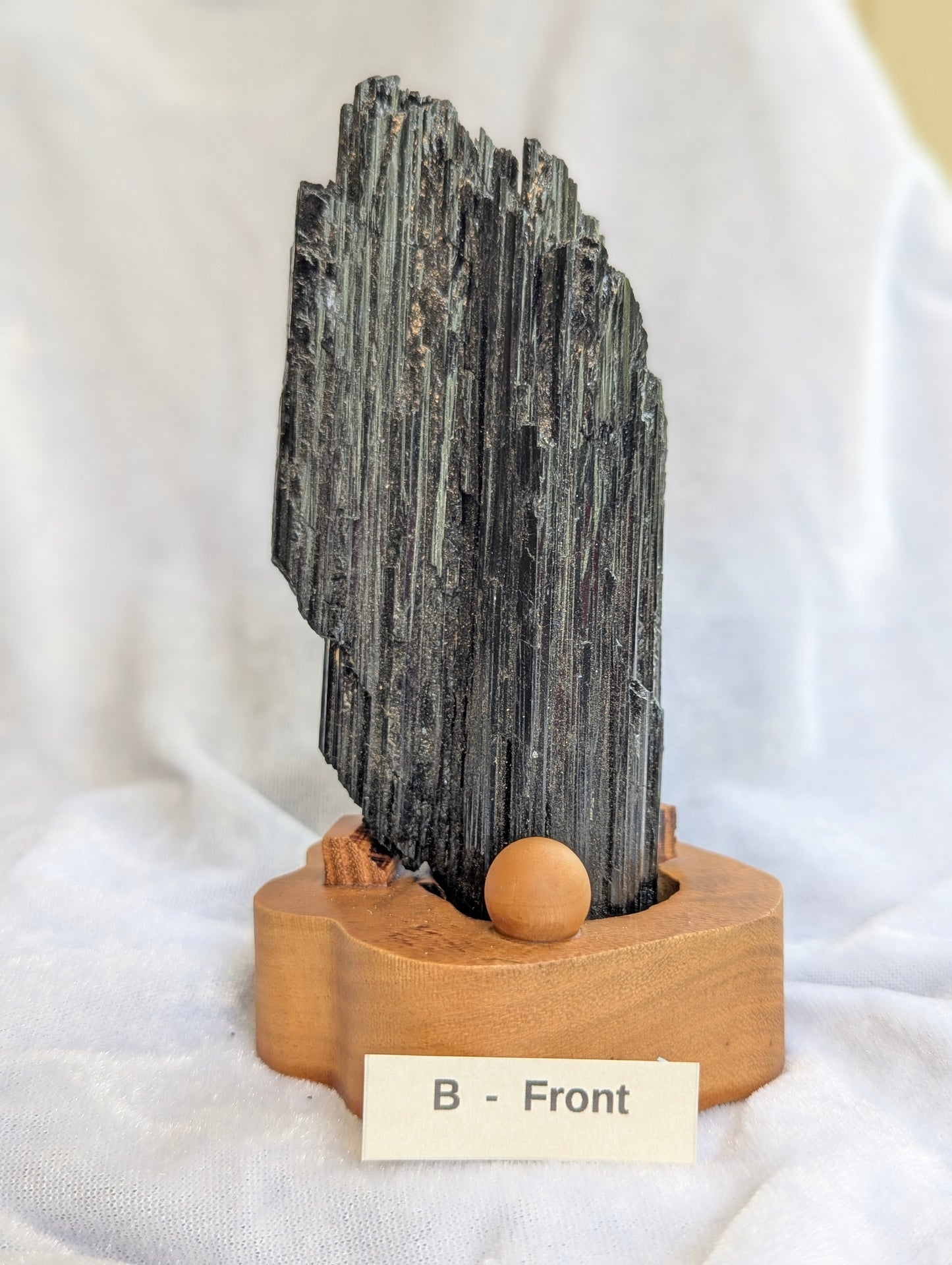 435g raw Black Tourmaline tower with heavy natural striations on wooden stand.