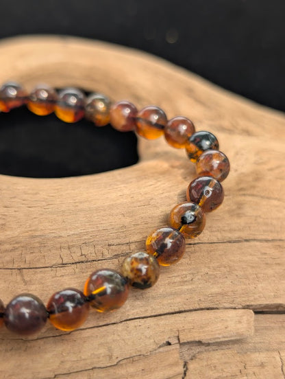 Macro view of 6mm Mexican Blue Amber spherical beads in natural light, highlighting organic internal inclusions within the honey-brown resin.