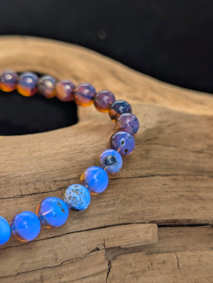 Macro view of 6mm Mexican Blue Amber spherical beads glowing electric blue under a UV light source.
