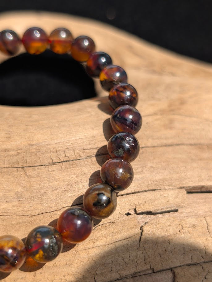 Close-up of polished 7mm Mexican Blue Amber beads, showing the rich, dark honey and cognac hues of the fossilized tree resin.