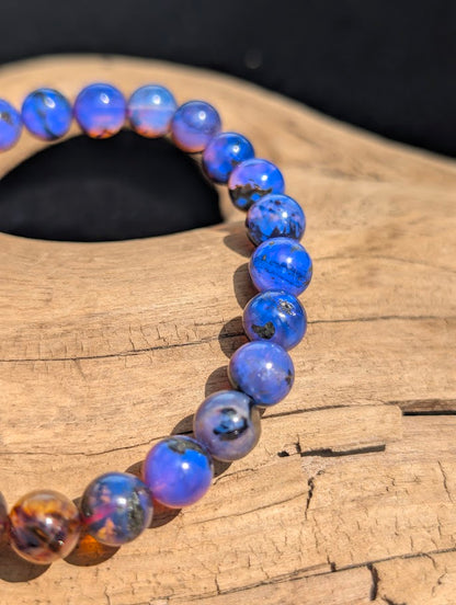 Close-up of 7mm Mexican Blue Amber beads actively fluorescing blue under ultraviolet light, proving its rare photoreactive properties.