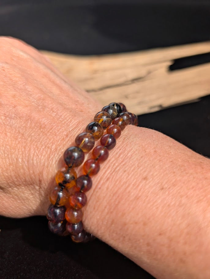 Natural sunlight on 6mm and 7mm Mexican Blue Amber stretch bracelets worn stacked on a wrist, showing their warm daylight colours.