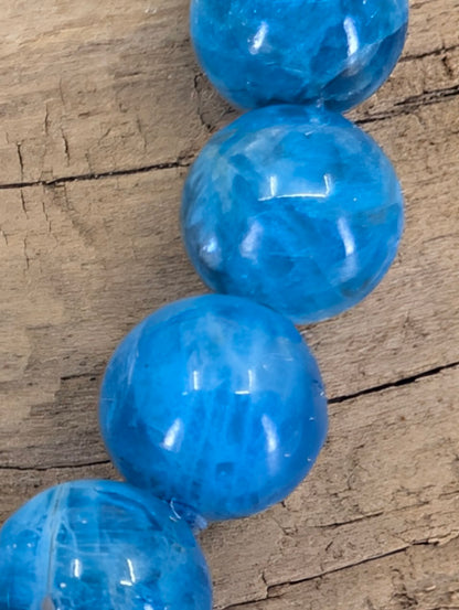 Macro close-up of Blue Apatite beads showing natural internal veils, vitreous luster, and oceanic color zoning.