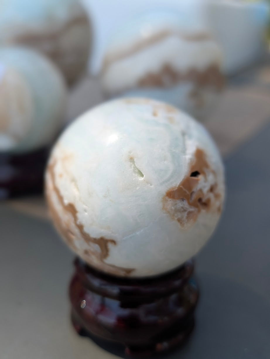 Side view of the 50mm Blue Aragonite sphere highlighting the smooth, pale seafoam-blue calcite surface.