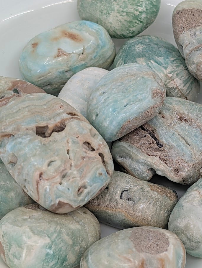 Close-up of Blue Aragonite tumbled stones showing swirling blue, cream, and tan layers