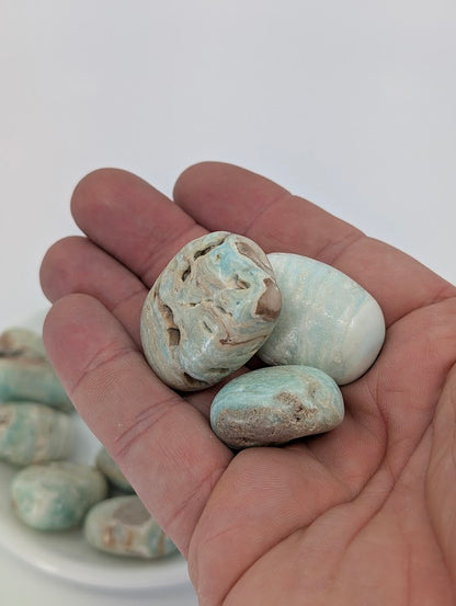 Hand holding Blue Aragonite tumbled stones highlighting natural patterning and smooth polish