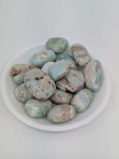 AA grade Blue Aragonite tumbled stones displayed in bowl showing ocean-blue and beige banding
