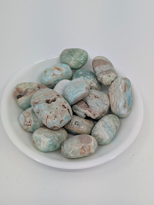 AA grade Blue Aragonite tumbled stones displayed in bowl showing ocean-blue and beige banding