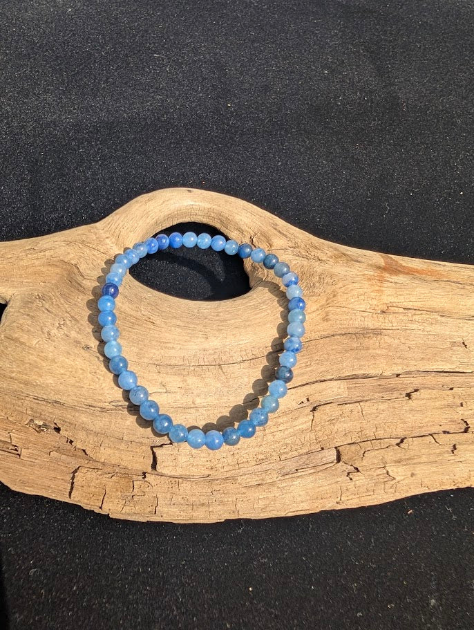 4mm Blue Aventurine beaded stretch bracelet resting on a driftwood display, showing soft denim blue colouration.